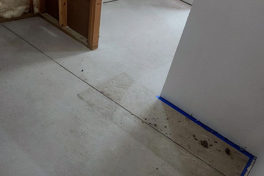 Bare, taped-off concrete in a utility room before the floor was installed