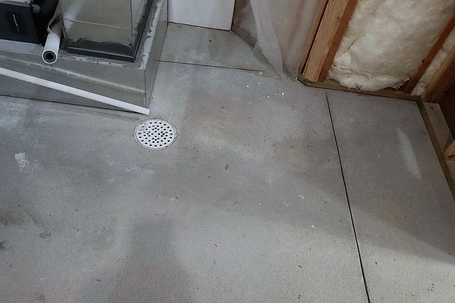 Bare concrete around a furnace and floor drain before installation