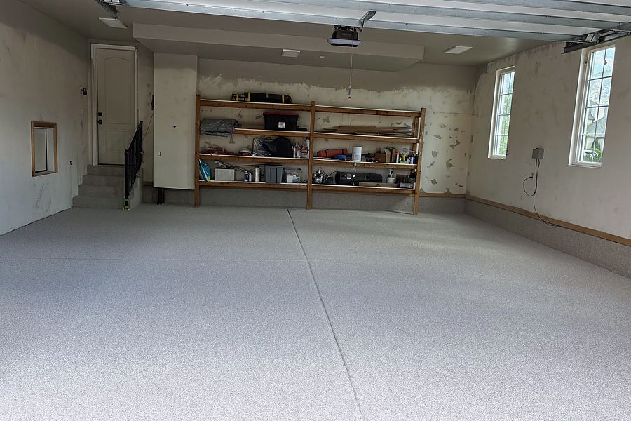 A garage with wooden shelving and a finished light flake floor